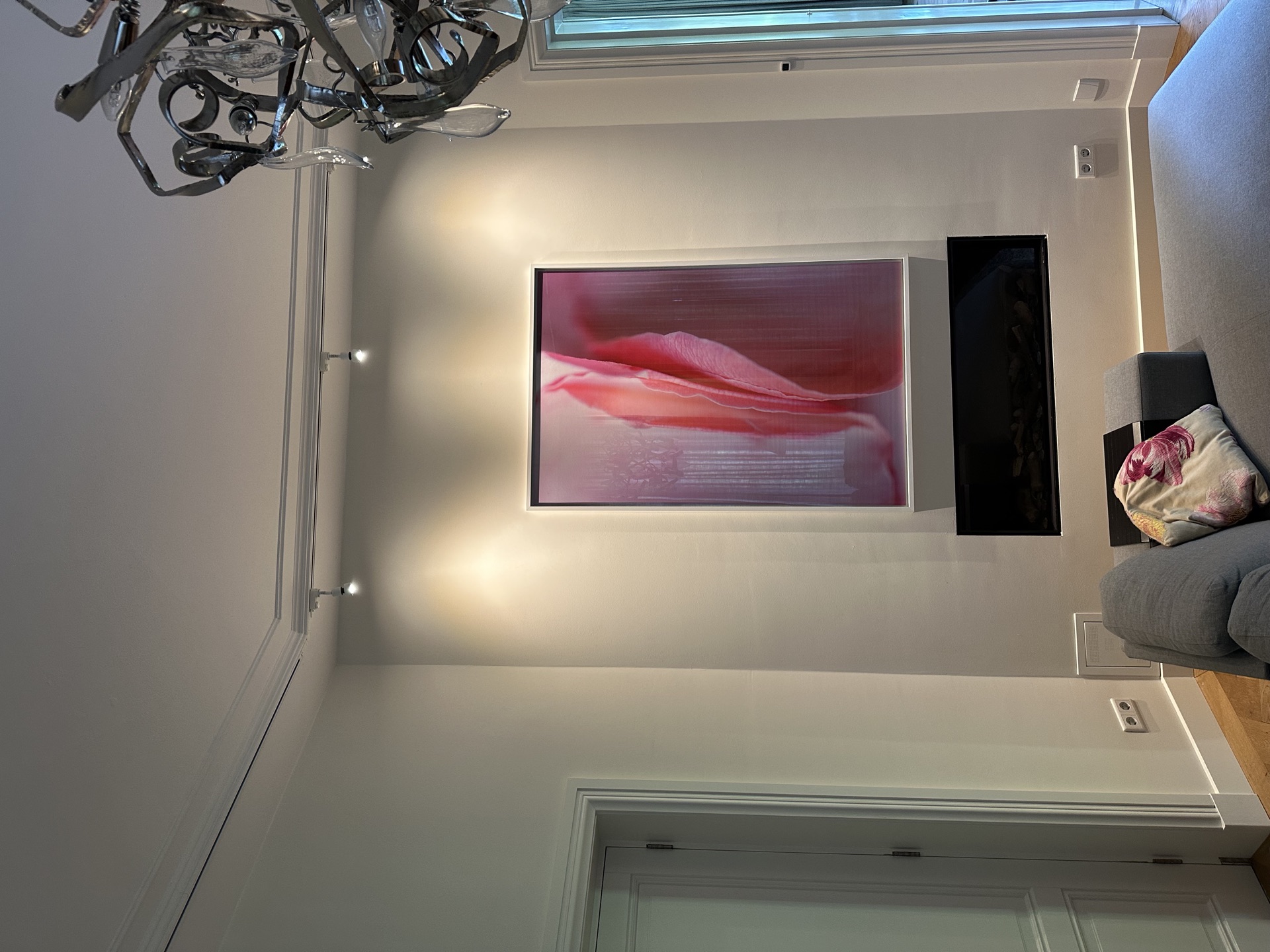 Bloemwerk boven de schouw in woonkamer met kroonluchter