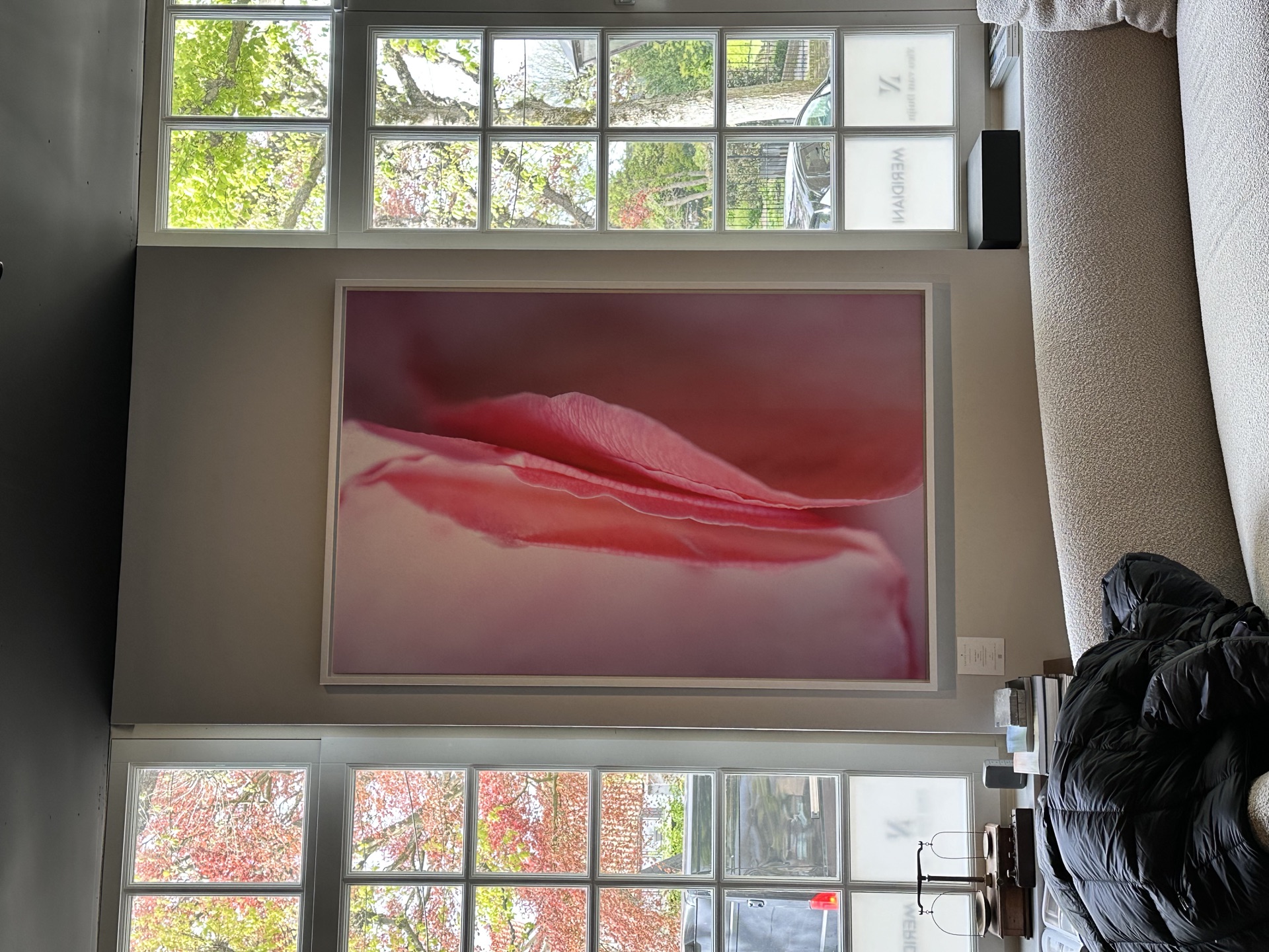 Groot roze bloemwerk tussen hoge ramen in woonkamer